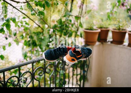 Sneaker per il lavaggio e l'asciugatura. Le briciole sono asciutte sul balcone. Scarpe che asciugano in modo naturale. Un paio di corone blu-arancioni. Foto Stock