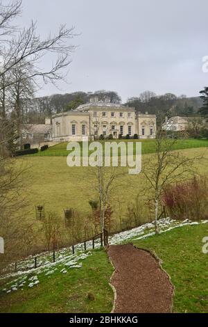 Un sentiero tra alberi e racchette da neve, che conduce attraverso il parco ad una tradizionale casa padronale inglese in pietra gialla, costruita nel 18 ° secolo Foto Stock