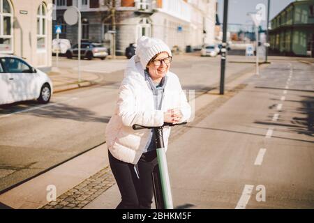 Donna turistica noleggio scooter elettrico in danimarca capitale Copenaghen. Manopola femmina sul piantone dello sterzo con maniglia elettrica per scooter da calcio sulla strada Foto Stock