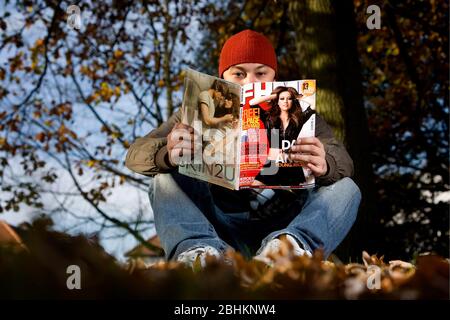 Un uomo la lettura di FHM magazine; un Bauer pubblicazione multimediale. Foto Stock