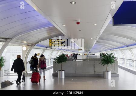 Terminal di trasferimento a piedi per i passeggeri dell'aeroporto di Manchester UK. Area arrivi con folla che si muove lungo il passerella Skylink travellator, collegando I terminal MAN. Foto Stock