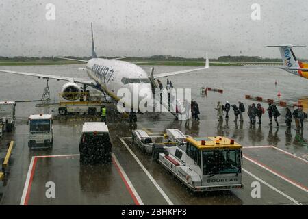 Aereo Manchester UK Ryanair con passeggeri a bordo al telicardello dell'aeroporto. Vista piovosa dei viaggiatori nell'area del grembiule entrando in un Boeing 737-800. Foto Stock