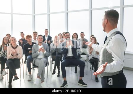 un diffusore sorridente davanti a un pubblico applaudente Foto Stock
