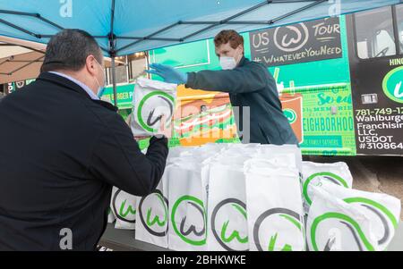 24 aprile 2020, Norwood, Massachusetts, USA: Il Rappresentante degli Stati Uniti Joe Kennedy III (D-ma) distribuisce un pasto gratuito con Whalburgers al membro di Teamsters Local 25 che guida per UPS, al di fuori di UPS Norwood. Whalburgers è di proprietà dello chef Paul Wahlberg, fratello di Donnie e Mark Wahlberg. Foto Stock