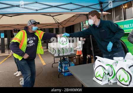 24 aprile 2020, Norwood, Massachusetts, USA: Il Rappresentante degli Stati Uniti Joe Kennedy III (D-ma) distribuisce un pasto gratuito con Whalburgers al membro di Teamsters Local 25 che guida per UPS, al di fuori di UPS Norwood. Whalburgers è di proprietà dello chef Paul Wahlberg, fratello di Donnie e Mark Wahlberg. Foto Stock