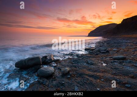 Seatown, Dorset, Regno Unito. 26 aprile 2020. Meteo Regno Unito. Le nuvole si illuminano di arancione al tramonto a Seatown nel Dorset guardando verso ovest verso le scogliere di Golden Cap. Credito immagine: Graham Hunt/Alamy Live News Foto Stock