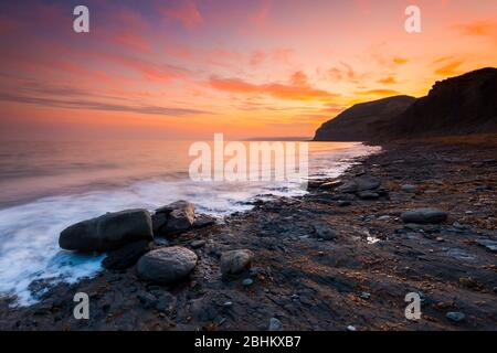 Seatown, Dorset, Regno Unito. 26 aprile 2020. Meteo Regno Unito. Le nuvole si illuminano di arancione al tramonto a Seatown nel Dorset guardando verso ovest verso le scogliere di Golden Cap. Credito immagine: Graham Hunt/Alamy Live News Foto Stock