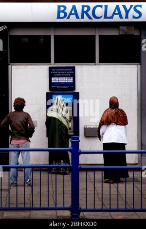 Donne velate usando un Barclays bancomat Foto Stock