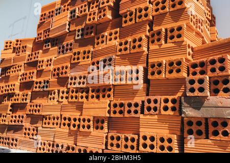 Mattoni rossi cavi impilati in un mucchio, pronti per l'uso in costruzione o per la vendita. Materiale da costruzione. Mattone ripiegato con precisione, foto per la pubblicità. Copia Foto Stock