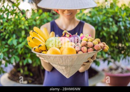 Varietà di frutta in un cappello vietnamita. Donna in un cappello vietnamita Foto Stock