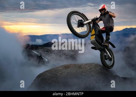 Extreme Adventure Man prova motociclette in cima a una roccia. Foto Stock