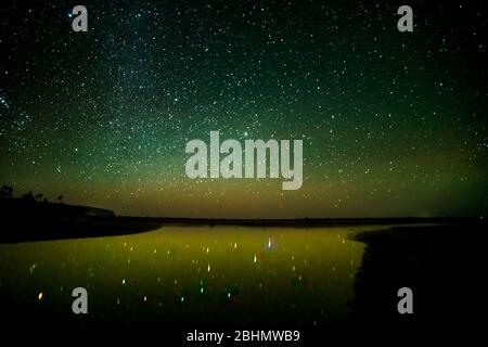 Milioni di stelle nel cielo notturno e riflessi stellato nell'insenatura e laguna sulla spiaggia Foto Stock