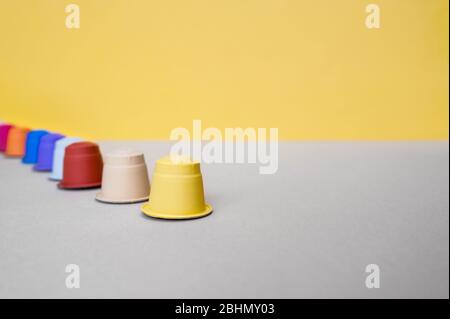 Capsule multicolore per macchina da caffè su fondo grigio-giallo Foto Stock