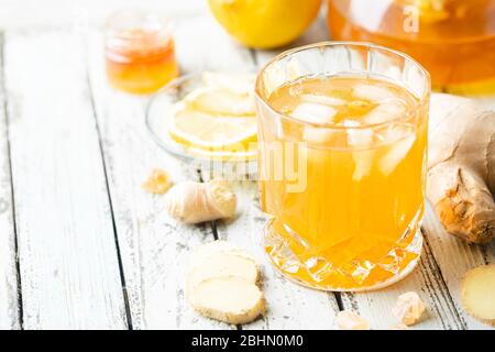 Bevanda gialla con zenzero, limone e ghiaccio in un bicchiere, rinfrescante limonata di zenzero fatto in casa o birra su sfondo bianco Foto Stock