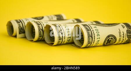 Dollari americani in rotoli. Risparmio di denaro su sfondo giallo con spazio di copia per il testo Foto Stock