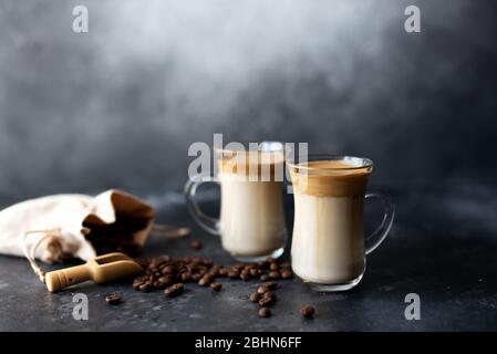Due tazze di vetro con caffè Dalgona frothy tendenza caffè espresso coreano bevanda latte con schiuma di caffè su fondo nero. Foto Stock
