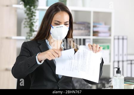 Donna executive con maschera protettiva che rompe contratto su una scrivania in ufficio Foto Stock