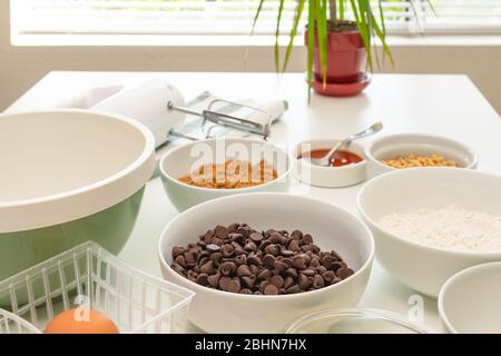 Le patatine di cioccolato e gli ingredienti per cuocere devono essere vicini su un tavolo da cucina. Ricetta dei biscotti del chip del cioccolato Foto Stock