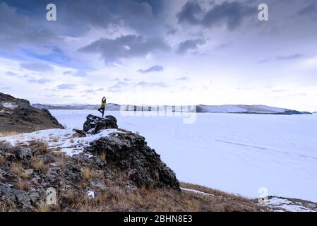 Lago Baikal, Russia - 9 marzo 2020: Scalatore di roccia sulla cima della roccia. Sport e vita attiva Foto Stock