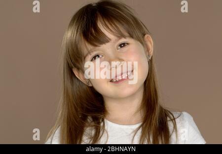 Ritratto di una bambina carina di 7 anni in una maglietta bianca, posa e sorridente Foto Stock