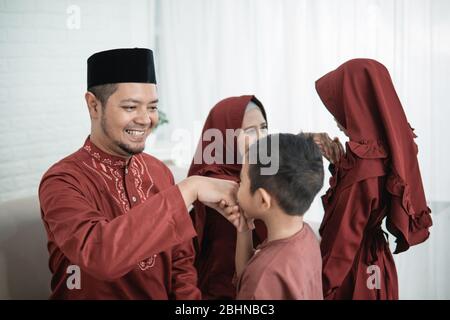 Bambino baciando la mano del padre per scusarsi e dire Happy Eid giorno Foto Stock