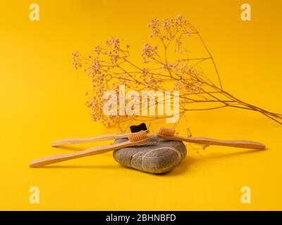 Spazzolini da denti in bambù di scarto su giallo Foto Stock