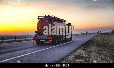 Un camion trasporta un serbatoio di combustibile su un'autostrada contro una foresta e un cielo blu. Il concetto di trasporto di merci pericolose su strada, l Foto Stock