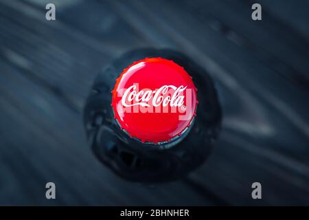 Kharkiv, Ucraina, 26 aprile 2020: Una bottiglia di vetro di coca-cola su sfondo scuro. Primo piano tappo rosso di bevanda, vista dall'alto. Editoriale illustrativo Foto Stock