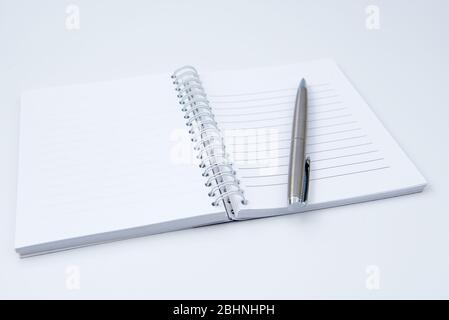Aprire il notebook con una penna su un tavolo da ufficio bianco Foto Stock