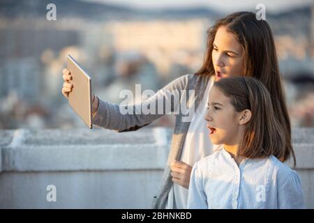 Due ragazze entusiaste che guardano contenuti multimediali utilizzando un tablet Foto Stock