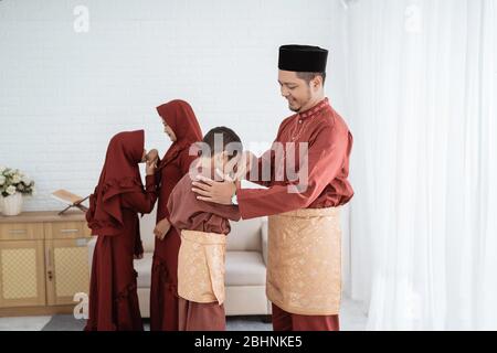 Bambini baciare la mano del genitore per scusarsi e augurare felice Ramadan Kareem Foto Stock
