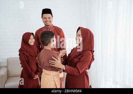 Bambini baciare la mano del genitore per scusarsi e augurare felice Ramadan Kareem Foto Stock