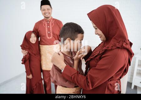 Bambini baciare la mano del genitore per scusarsi e augurare felice Ramadan Kareem Foto Stock