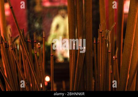 Incenso bastone bruciare in primo piano con in altare sfocato in background. Tempio di Hong Kong Foto Stock