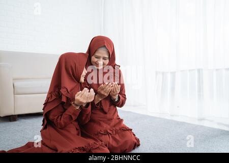 Madre e figlia musulmana che pregano insieme a casa Foto Stock