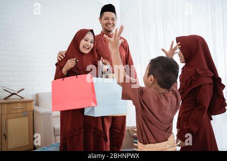 La madre hijab dà i regali ai loro bambini usando i sacchetti di carta su Eid al-Fitr Foto Stock