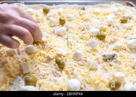 Donna che spalma formaggio che cucina pizza o flammkuchen a casa Foto Stock