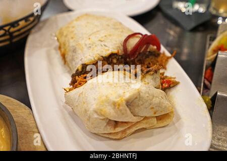 Burrito di pollo, cucina messicana e Tex-Mex consiste di una tortilla di farina con vari altri ingredienti avvolti in un cilindro chiuso a forma di cilindro Foto Stock