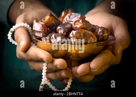 IFTAR immagine mano che tiene date frutta con Tasbeeh, mese santo islamico Festival concetto sfondo ramadan saluti Foto Stock
