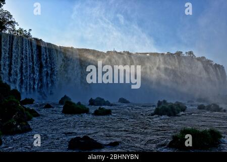 Sunbeams Mist e spruzzi con i torrenti che arrivano sopra la cascata della Gola del Diavolo alle Cascate di Iguacu, Brasile Foto Stock