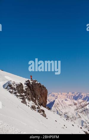 Un uomo si trova in cima a una montagna e fotografa la vista sul suo smartphone. Foto Stock