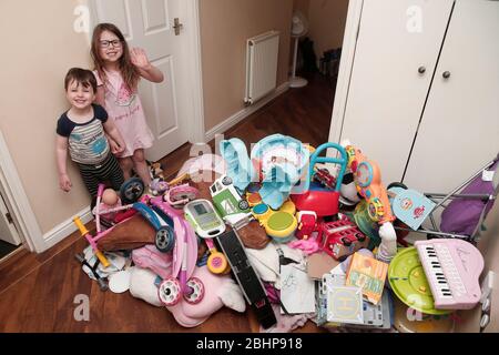 Due fratelli circondati da un enorme mucchio di giocattoli per bambini a casa Foto Stock