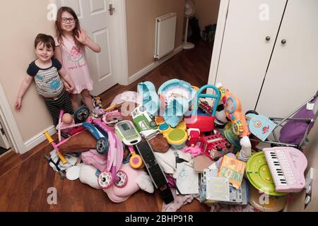 Due fratelli circondati da un enorme mucchio di giocattoli per bambini a casa Foto Stock