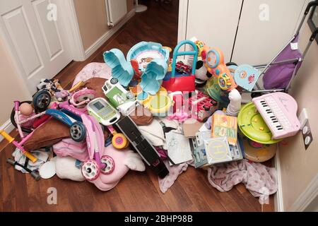 Due fratelli circondati da un enorme mucchio di giocattoli per bambini a casa Foto Stock