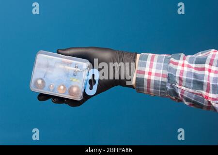 Luci e materiale di ricambio obbligatorio per auto in una scatola di plastica e a portata di mano con guanto nero e sfondo blu Foto Stock