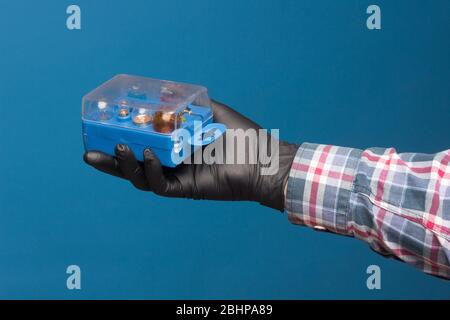 Luci e materiale di ricambio obbligatorio per auto in una scatola di plastica e a portata di mano con guanto nero e sfondo blu Foto Stock