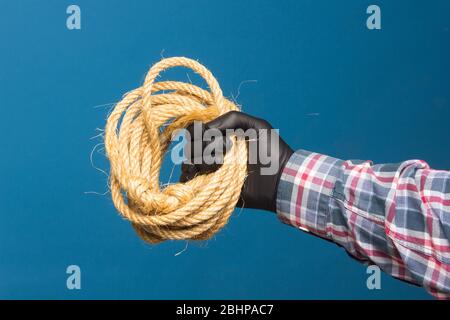 Corda gialla nella mano esperta di un adulto con protezione. Corda spessa per legare oggetti. Foto Stock