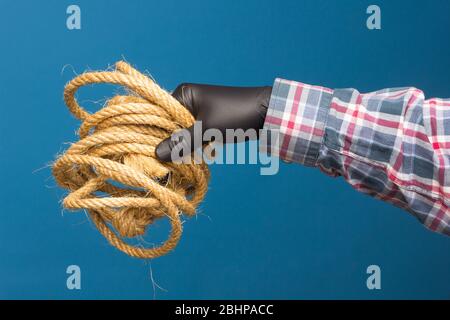 Corda gialla nella mano esperta di un adulto con protezione. Corda spessa per legare oggetti. Foto Stock