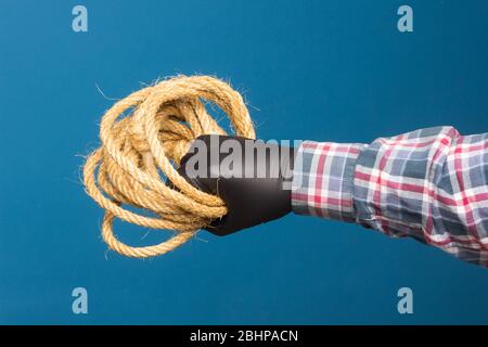 Corda gialla nella mano esperta di un adulto con protezione. Corda spessa per legare oggetti. Foto Stock