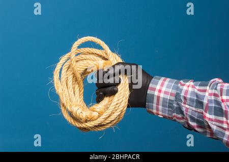 Corda gialla nella mano esperta di un adulto con protezione. Corda spessa per legare oggetti. Foto Stock